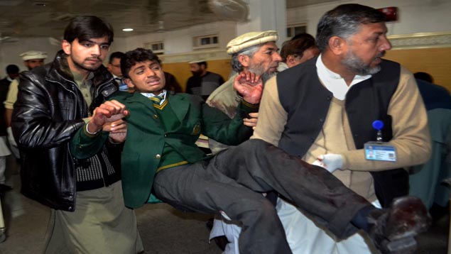 Pakistani volunteers carry a student injured in the shootout at a sch