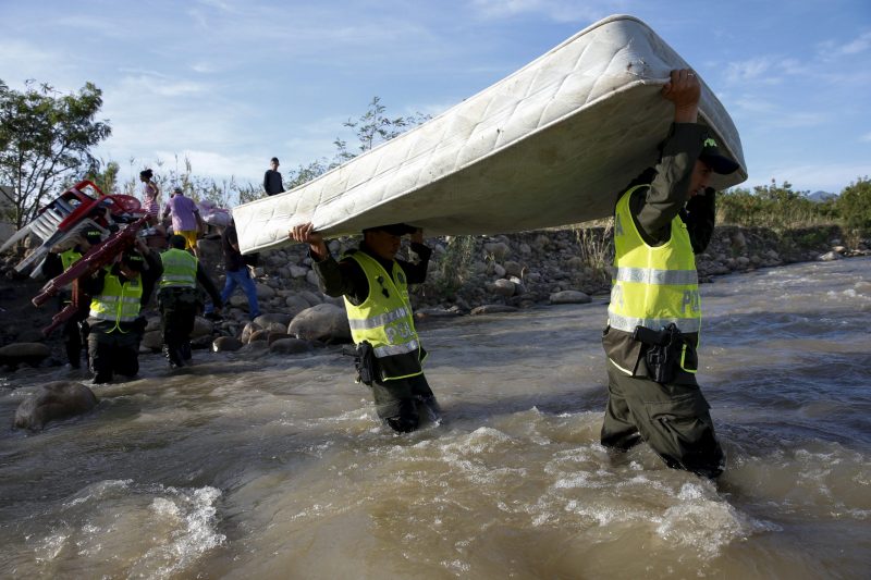 Colombian policemen carry a mattress as they help people to cross with their belongings to Colombia, through the Tachira River at San Antonio in Tachira state