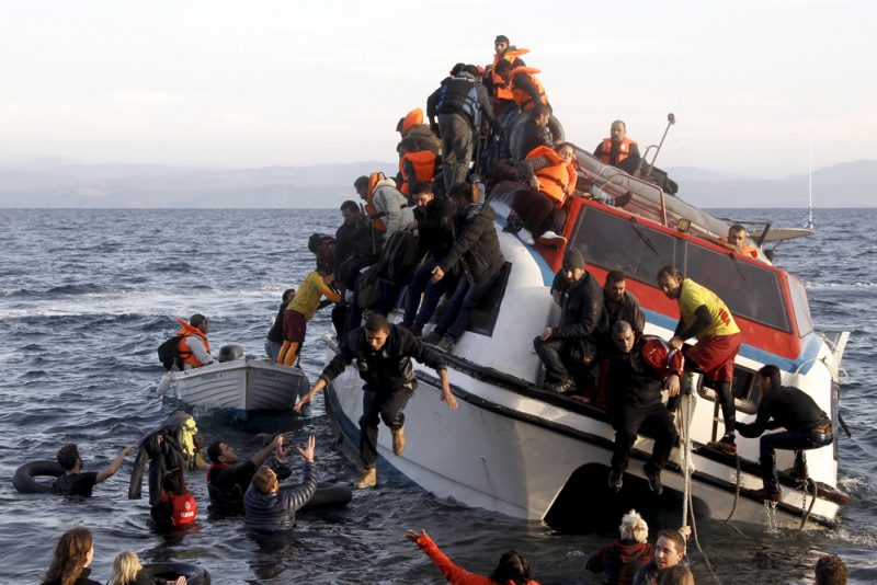 Refugees, most of them Syrians, struggle to leave a half-sunken catamaran carrying around 150 refugees as it arrives on the Greek island of Lesbos