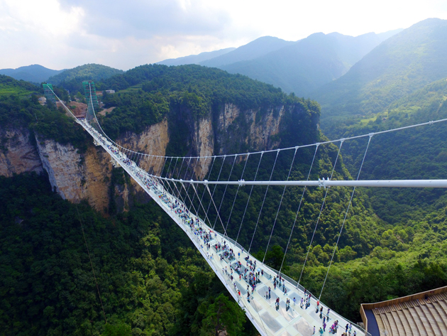 FUZ01. Zhangjiajie (China), 20/08/2016.- Tourists walk on the glass-floor suspension bridge in Zhangjiajie, south China's Hunan province, 20 August 2016, the first day of its trial operation. The 375-meters long bridge, featuring 99 pieces of five-centimeter-thick reinforced glass as its floor, spans some 300 meters above the bottom of the Karst valley in the scenic zone. It is both the longest and the highest glass bridge in the world. EFE/EPA/SHAO YING CHINA OUT