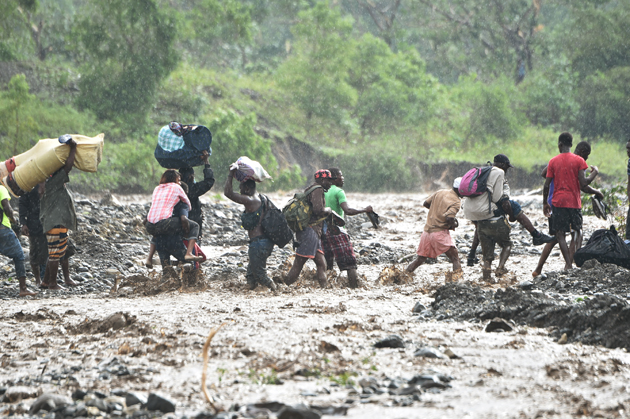 Haitian people cross the river La Digue in Petit Goave where the bridge collapsed during the rains of the Hurricane Matthew, southwest of Port-au-Prince, October 5, 2016. Haiti and the eastern tip of Cuba -- blasted by Matthew on October 4, 2016 -- began the messy and probably grim task of assessing the storm's toll. Matthew hit them as a Category Four hurricane but has since been downgraded to three, on a scale of five, by the US National Hurricane Center. / AFP PHOTO / HECTOR RETAMAL